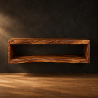 Floating wooden bathroom vanity with a slab top and an open shelf below in a dark studio against a charcoal plaster wall