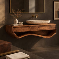 Corner detail of floating wood vanity cabinet with a sweeping wave shaped open shelf underneath beside wood, brass and linen samples