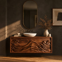 Floating bathroom vanity with two doors carved in ocean waves in a dark studio against a charcoal plaster wall