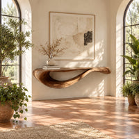 Floating console table with a sweeping wave shaped underside in a bright entryway with arched windows and plants