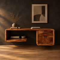 Floating desk with a soft edged body, open cubby shelf and two drawers in a dark studio against a charcoal plaster wall