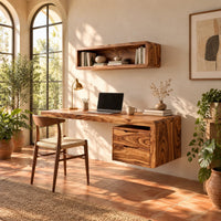 Floating desk with a thick grained top and a hanging two drawer pedestal in a bright home office with arched windows and plants