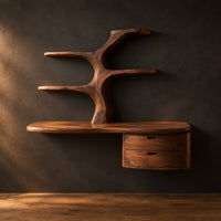 Floating desk with a tree trunk, branch shelves and two drawers in a dark studio against a charcoal plaster wall