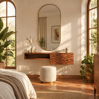 Floating makeup vanity with an open niche and a wave carved front panel in a bright bedroom with arched windows and plants