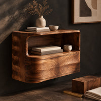 Corner detail of floating nightstand with a curved open shelf and wavy carved sides beside wood, brass and linen samples