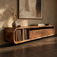 Corner detail of low floating tv stand with open vinyl slots and two wide front panels beside wood, brass and linen samples