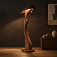 Floor lamp with a bowed stem and a hooded leaf shade in a dark studio against a charcoal plaster wall