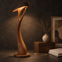 Corner detail of floor lamp with a bowed stem and a hooded leaf shade beside wood, brass and linen samples