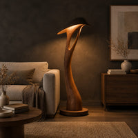 Floor lamp with a bowed stem and a hooded leaf shade in a dark living room at golden hour