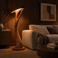 Floor lamp with a bowed stem and a hooded leaf shade in an evening living room with walnut wall paneling