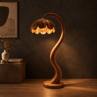 Floor lamp with an arching stem and a petal shaped shade in a dark studio against a charcoal plaster wall