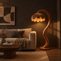 Floor lamp with an arching stem and a petal shaped shade in a dark living room at golden hour
