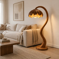 Floor lamp with an arching stem and a petal shaped shade in a Scandinavian living room with white walls