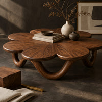 Corner detail of flower shaped coffee table on a looping wave base beside wood, brass and linen samples