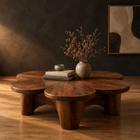 Petal shaped coffee table on thick round legs in a dark studio against a charcoal plaster wall