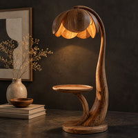 Corner detail of wooden floor lamp with a flower shaped petal shade, arched stem and side tray beside wood, brass and linen samples