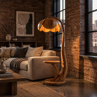 Wooden floor lamp with a flower shaped petal shade, arched stem and side tray in an industrial loft living room with exposed brick