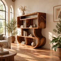 Bookshelf with stacked open cubbies and flowing sculpted sides in a bright living room with arched windows and plants