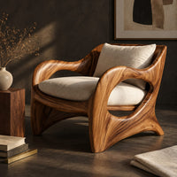 Corner detail of wooden chair with sweeping open arms and cream seat and back cushions beside wood, brass and linen samples