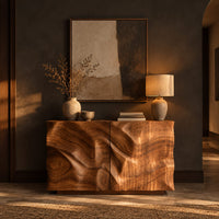 Console table cabinet with two doors carved in flowing wood grain relief in a dark entryway at golden hour