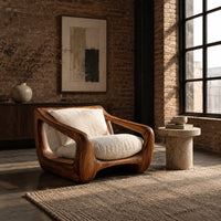 Wooden lounge chair with open sculpted arms and a cushioned seat in an industrial loft living room with exposed brick