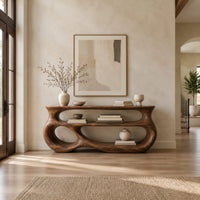 Console table with a sculpted open loop body and stacked oval shelves in a bright open plan entryway