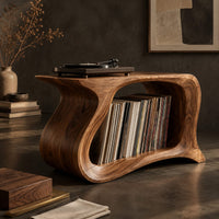 Corner detail of record player stand with a flowing wave shaped body and one wide open bay beside wood, brass and linen samples