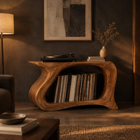 Record player stand with a flowing wave shaped body and one wide open bay in a dark living room at golden hour