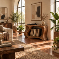 Record player stand with a flowing wave shaped body and one wide open bay in a bright living room with arched windows and plants