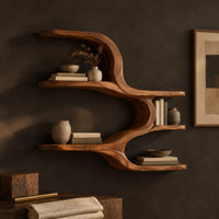 Corner detail of wall shelf with four open levels joined by a flowing wave form beside wood, brass and linen samples