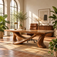 Smooth slab desk on a flowing sculpted base with an oval opening in a bright home office with arched windows and plants
