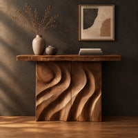 Console table with deep flowing swirl carving and a slab top in a dark studio against a charcoal plaster wall