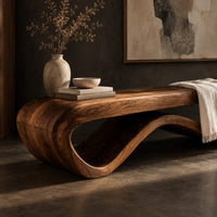 Corner detail of long bench with a flat slab seat on a flowing wave base beside wood, brass and linen samples