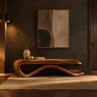 Long bench with a flat slab seat on a flowing wave base in a dark entryway at golden hour