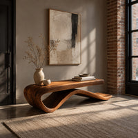 Long bench with a flat slab seat on a flowing wave base in an industrial loft entryway with exposed brick