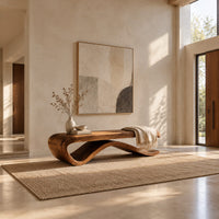 Long bench with a flat slab seat on a flowing wave base in a bright open plan entryway