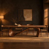 Dining table with a long smooth top on one flowing wave shaped base in a dark dining room at golden hour