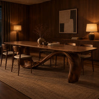 Dining table with a long smooth top on one flowing wave shaped base in an evening dining room with walnut wall paneling