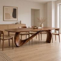 Dining table with a long smooth top on one flowing wave shaped base in a Scandinavian dining room with white walls