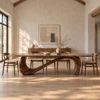 Dining table with a long smooth top on one flowing wave shaped base in a bright open plan dining room