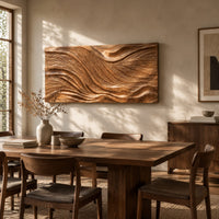 Wide wooden wall art panel with a flowing carved wave relief beside a dining table in natural light