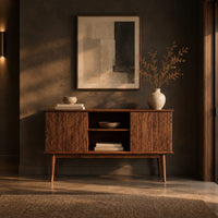 Console cabinet with fluted side doors, an open center shelf and tapered legs in a dark entryway at golden hour