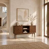 Console cabinet with fluted side doors, an open center shelf and tapered legs in a bright open plan entryway