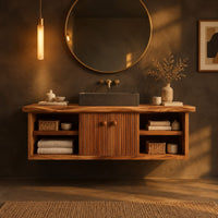 Floating vanity with fluted doors and open side shelves on both ends in a dark bathroom at golden hour