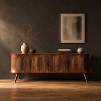 Long sideboard with vertical fluted doors on slim tapered legs in a dark studio against a charcoal plaster wall