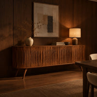 Long sideboard with vertical fluted doors on slim tapered legs in an evening dining room with walnut wall paneling