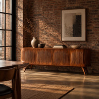 Long sideboard with vertical fluted doors on slim tapered legs in an industrial loft dining room with exposed brick