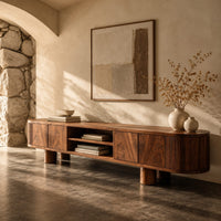 Corner detail of low media stand with fluted ends, grain front panels and thick cylinder feet beside wood, brass and linen samples