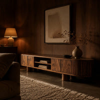 Low media stand with fluted ends, grain front panels and thick cylinder feet in an evening living room with walnut wall paneling