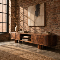 Low media stand with fluted ends, grain front panels and thick cylinder feet in an industrial loft living room with exposed brick